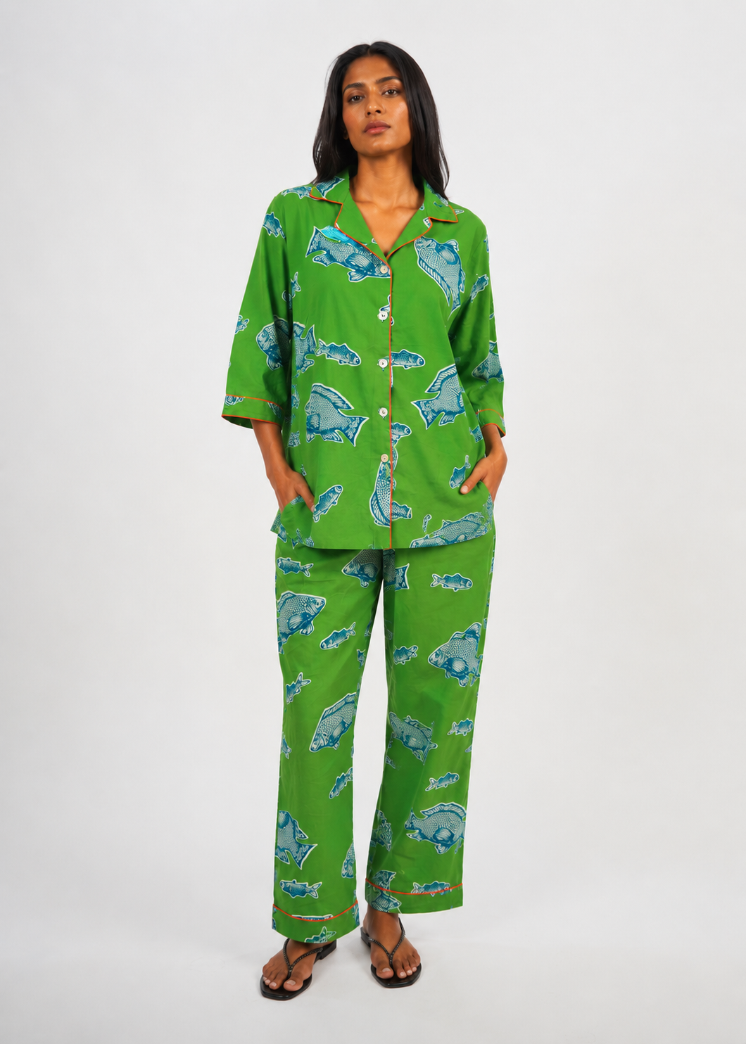 Woman wearing a green pajama set with blue fish pattern on a white background